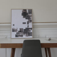 a work table with a thin oak frame standing on it with an art print inside with the title Selected Blacks 06