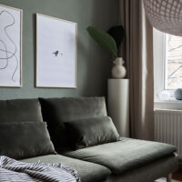 a living room with dark green walls and couch with two art prints on the wall with the title; The Pen 02 and The Dot