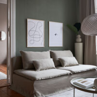 a living room with dark green walls and a beige couch with two art prints on the wall with the title; The Pen 02 and The Dot