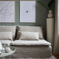 a living room with dark green walls and a beige couch with two art prints on the wall with the title; The Pen 02 and The Dot